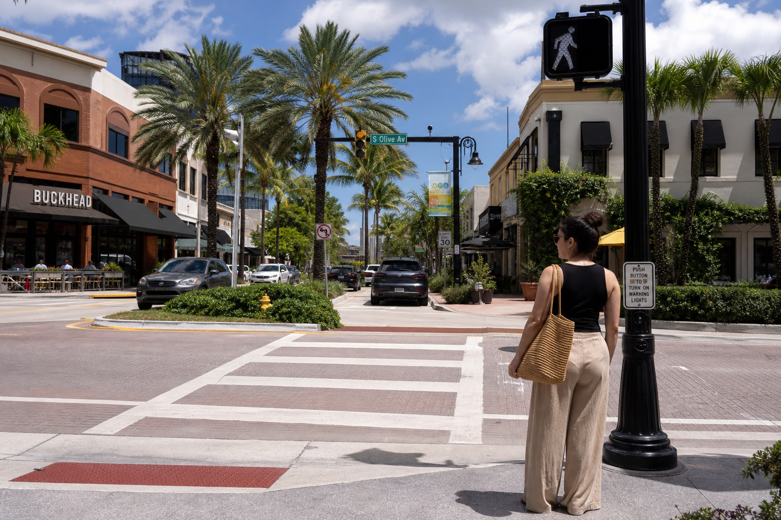 Pedestrian waiting at a crosswalk in a sunny Florida downtown